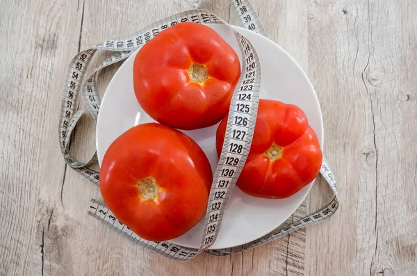 減量と健康的な食事の概念 プレートに赤いトマトと木製のテーブルの上にテープを測定します 接近中だ 最上階だ トマトダイエット — ストック写真