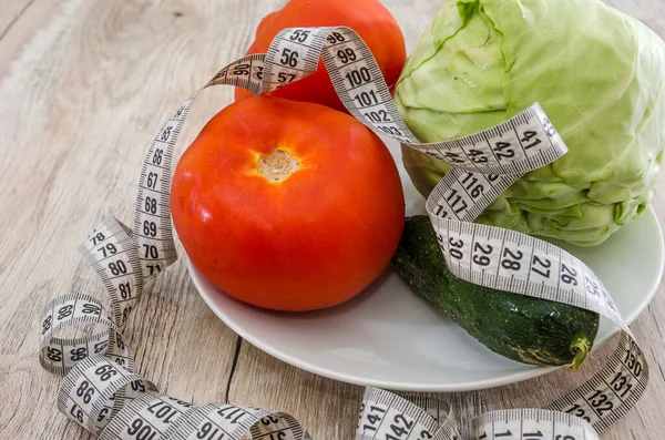 減量と健康的な食事の概念 板の野菜や木のテーブルの上でテープを測定します — ストック写真