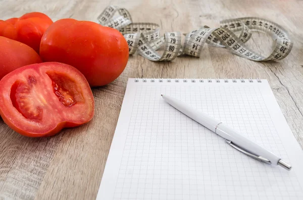 木製のテーブルの上にペン 測定テープ トマトと白いノートブック 減量と健康的な食事の概念 — ストック写真