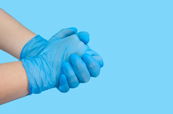 Individual protection products vinyl disposable gloves in the spread of virus and protection against infections. Women \'s hands in gloves. Copy of space. Blue background.