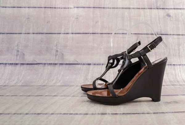brown women's sandals with a large heel on a wooden background. Fashionable summer sandals. Side view. Copy of space.