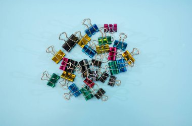 Mavi arkaplanda renkli ofis kağıdı ataçları.