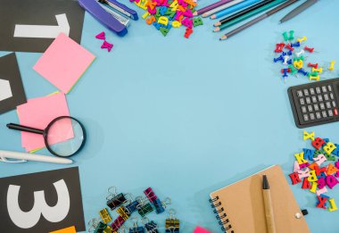 Ofis malzemeleri mavi arka planda. Uzayın kopyası. Resimler için bir yer. Not defteri, kalem, hesap makinesi, zımba, düğme ve büyüteç.