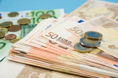 50 Euro ve bozukluklarla dolu bir yığın. Mavi arka plan. Yakın plan. Finansal konsept. Bir sürü euro banknotları..