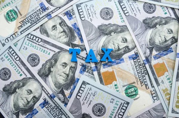 Das Wort Steuer Aus Buchstaben Auf Einem Hintergrund Von Dollar — Stockfoto
