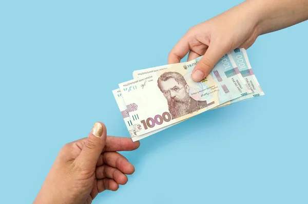 Kadın ellerinde 1000 Hryvnia. Yozlaşma kavramı. Rüşvet vermek için. Dolar ver ya da al. Mavi arka planda izole edilmiş Hryvnias 'lı eller.