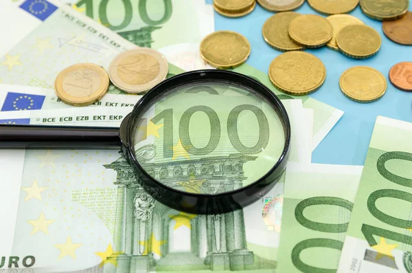 100 Euro Durch Lupe Und Münzen Blauer Hintergrund Finanzkonzept — Stockfoto