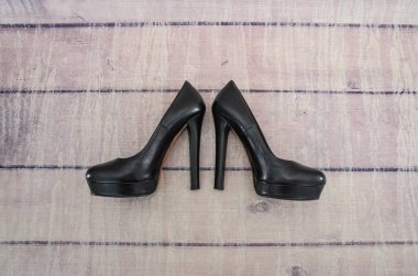 Ahşap arka planda siyah topuklu kadın ayakkabıları..