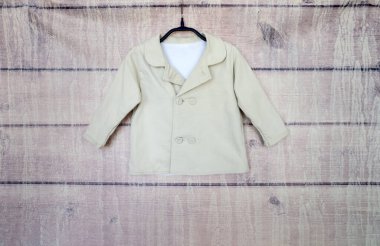Ahşap bir arka plandaki askıda açık renk ceket..