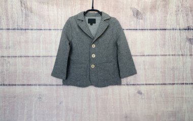 Ahşap bir arka planda askıda gri bir ceket.