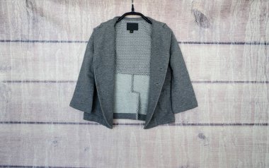 Ahşap bir arka plandaki askıda düğmesiz gri ceket..