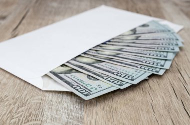 Tahta bir masanın üzerinde 100 dolarlık banknotlar olan zarf. Zenginlik ve refah kavramı. 