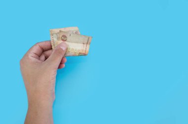 Mavi arka planda izole edilmiş bir kadın elinde iki hryvnia. Kriz ya da yoksulluk kavramı. Boşluğun kopyası.