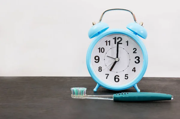 黒いテーブルの上に青い目覚まし時計と歯ブラシ 歯を磨く時間の概念 宇宙のコピー テキストの場所 — ストック写真