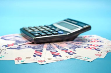 Hesap makinesi ve mavi arka planda 200 Hryvnia banknotu. Finansal konsept. Tasarruf kavramı, ekonomik kriz.