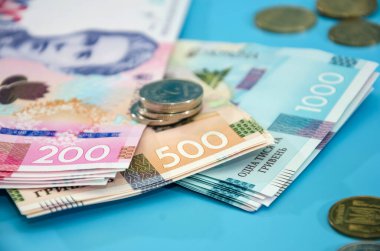 Mavi arka planda yeni Ukrayna banknotları ve sikkeleri. Bir yığın Hryvnia. Yakın plan..