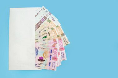 Mavi arka planda izole edilmiş beyaz bir zarfın içinde Ukrayna Hryvnia 'sı. Uzayın kopyası. 200, 500, 1000 hryvnias. Mali konsept.