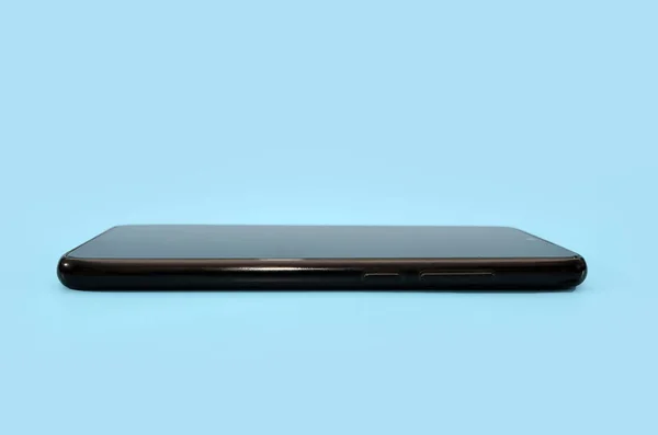 青い背景に黒いスマートフォン — ストック写真