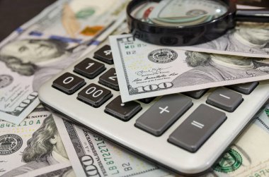 Dolar, hesap makinesi ve büyüteç. Finansal konsept. Yakın plan.