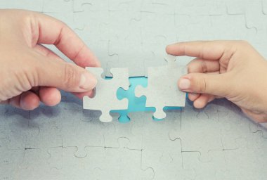 Eller bulmacanın son parçasını yerleştirir. Yakın plan. Eller maviye bağlanıyor.