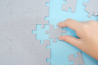 Mavi arkaplana elle yerleştirilmiş bulmaca parçası.