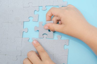 Mavi arkaplana elle yerleştirilmiş bulmaca parçası.