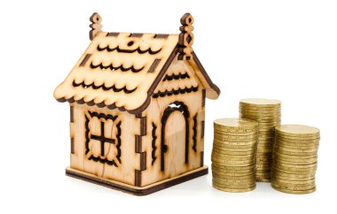 Mini ahşap ev, beyaza izole edilmiş madeni paralar. Gayrimenkul ya da gayrimenkul yatırımı. Konut kredisi oranı. Para biriktiriliyor.