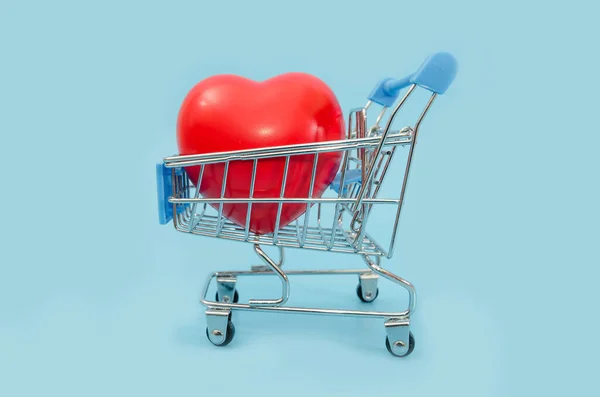 青い背景のショッピングカートの赤いハート — ストック写真