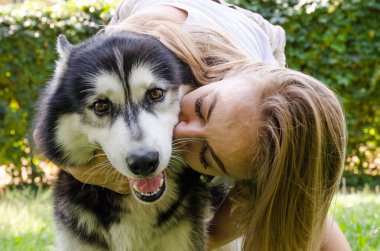 Genç ve güzel bir kız bir köpeği öpüyor..