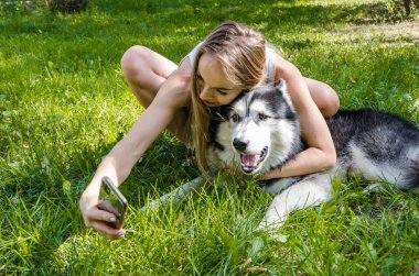 Genç ve güzel bir kız parkta bir köpekle selfie çekiyor..