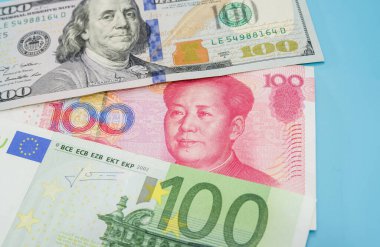 Dolarlar, Yuan, Avro banknotları mavi arka planda.