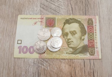 100 Hryvnia banknotu ve ahşap arka planda paralar. Yukarıdan görüntüle.