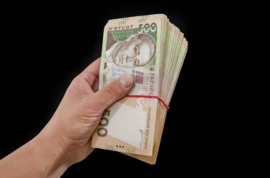 Kadın eli, siyah arka planda izole edilmiş bir yığın Hryvnia 'yı tutuyor. 500 Hryvnia.