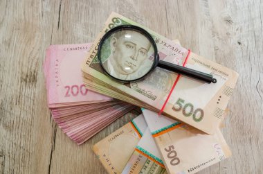 Hryvnia demetleri ve ahşap bir arka planda büyüteç. Ukrayna parası. 500 ve 200 Hryvnia banknotları. Paketin üzerinde 