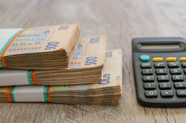 Tahta bir masada üç deste Hryvnia ve bir hesap makinesi. Ukrayna parası. 500 Hryvnia banknotları. Bir sürü Ukrayna parası..