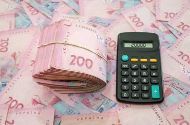 200 Hryvnia, elastik bant ve hesap makinesiyle bağlı. Finansal konsept. Bir sürü banknot..