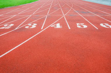 Stadyumda kırmızı koşu izleri var. Beyaz çizgiler, sayılar