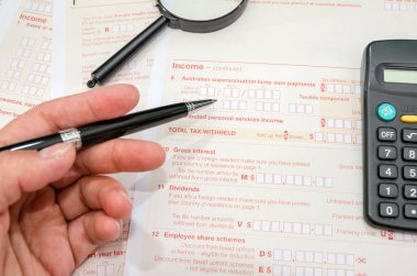 Avustralya vergi formlarını dolduran bir kadının eline kalemle yakın çekim. Finansal belge. Vergi zamanı. Yakın plan..