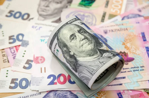 Yuvarlanmış 100 dolarlık banknot arka planda Hryvnia ile birlikte duruyor. Hryvnia 'nın dolara oranı. Değişim oranları.