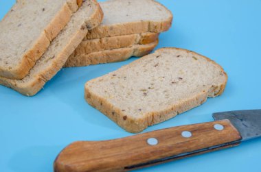 Mavi arka planda kepek ve bıçaklı çavdar ekmeği dilimleri. Dilimlenmiş siyah ekmek