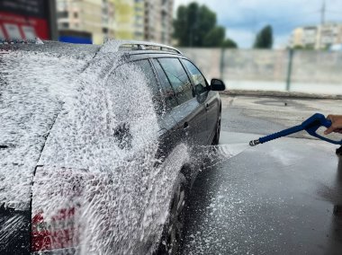 Bir adam arabasını self-servis lavabosunda yıkıyor. araba yıkama konsepti.