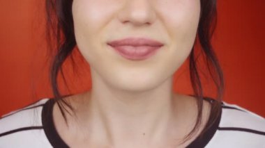 Parlak kırmızı arka planda muhteşem dudakları olan esmer bir kız. Mutlu kadın kameraya hava öpücüğü gönderiyor, dudaklar kapalı..