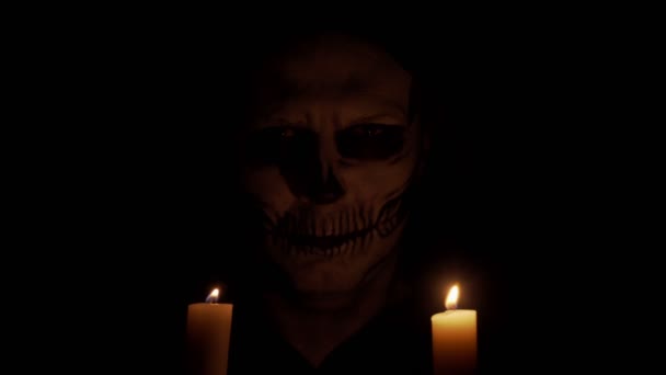 一个骨瘦如柴的男人在看着摄像机 骷髅在昏暗的烛光中 万圣节和恐怖概念 — 图库视频影像