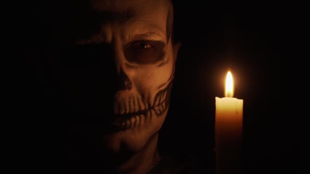 一个骨瘦如柴的男人看着摄像机 这个人很生气 施了一个咒语 骷髅在昏暗的烛光中 万圣节和恐怖概念 — 图库视频影像