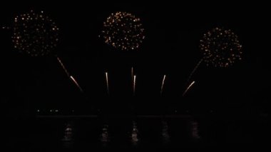 Gece gökyüzünde Bokeh ışıkları olan büyük, altın gibi havai fişekler. Parlak havai fişek gösterisi. Yeni yıl arifesi havai fişek kutlaması. Havai fişek Festivali.