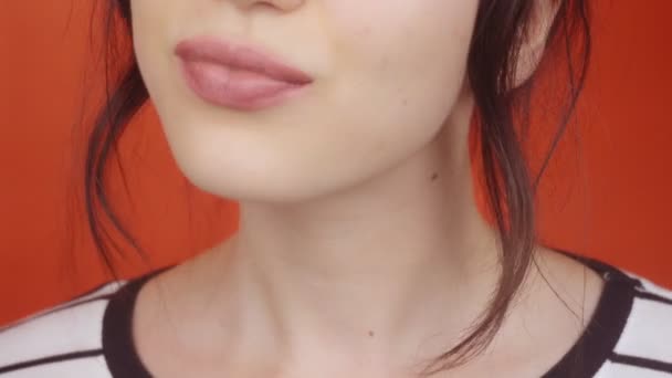 明るい赤の背景に豪華な唇を持つ若いブルネットの女の子 幸せな女性は カメラに空気のキスを送信 唇を閉じます — ストック動画