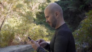 Yetişkin adam orman arka planında cep telefonu kullanıyor.