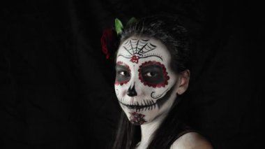 Meksika Ölüler Günü. Şeker kafalı, Cadılar Bayramı makyajlı genç bir kadın kameraya bakıyor. Kadın yüzündeki maskeyi çıkartıyor. Mutlu Cadılar Bayramı. Yüksek kalite 4k video