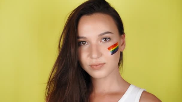 脸上挂着彩虹图案的快乐女人会送出一个飞吻 Lgbt旗被画在脸上 黄色背景 — 图库视频影像
