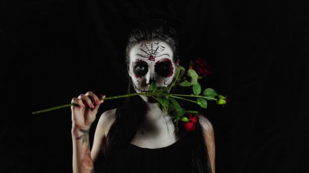 万圣节面具Calavera Catrina 手里拿着玫瑰的女孩墨西哥死者纪念日 一个年轻女子的肖像 在黑暗的背景下 有着可怕的多彩的万圣节化妆 — 图库视频影像